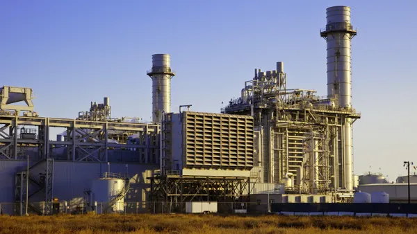 A natural gas-fired turbine power plant with it's cooling towers rising into a blue sky.